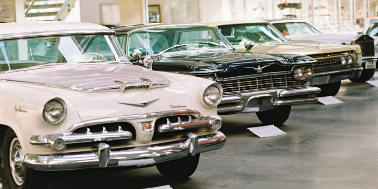 Row of vintage classic cars parked inside a bright museum gallery, a typical car lover's day out