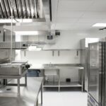 Back-of-house commercial kitchen with stainless steel refrigeration, extraction canopy and storage racking, as prepared during installation