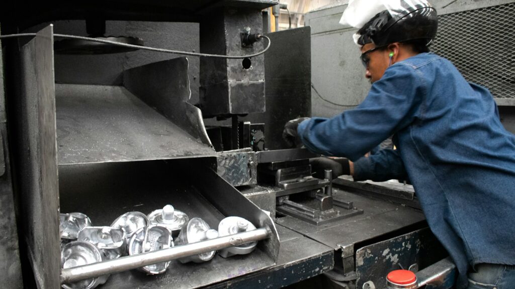 A man working at a machine in a factory, illustrating production scheduling for surface-treated metal parts