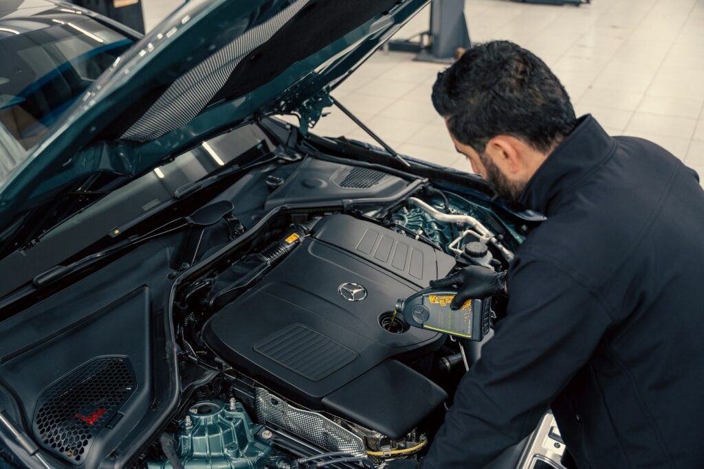 Mechanic inspecting a car engine with the bonnet open ahead of an MOT test