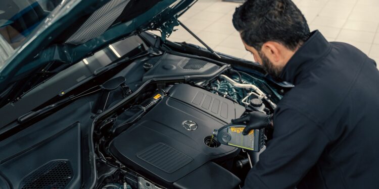 Mechanic inspecting a car engine with the bonnet open ahead of an MOT test