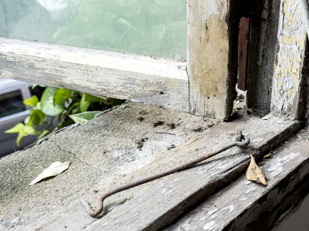 Close-up of an old, weathered window latch on a sash window showing signs of age