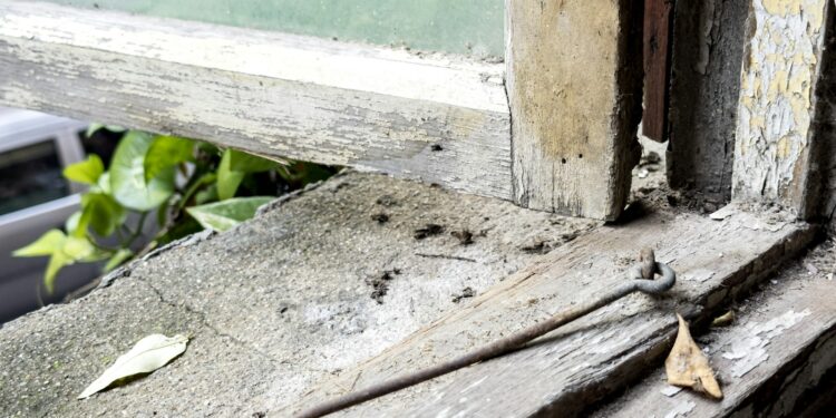 Close-up of an old, weathered window latch on a sash window showing signs of age