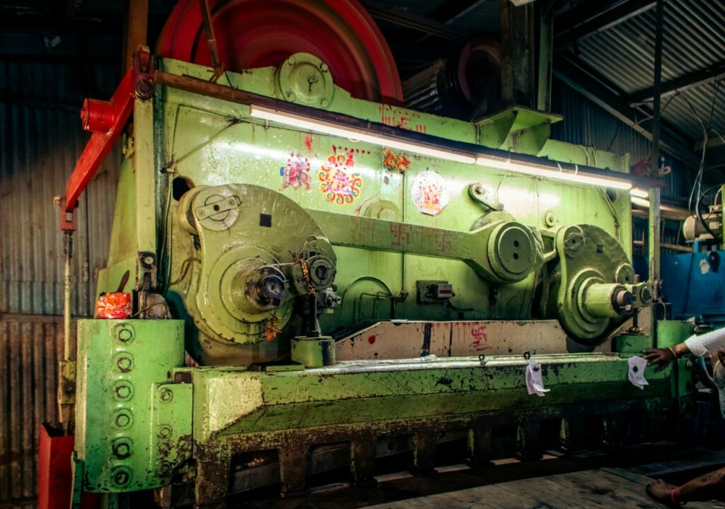 Large industrial shearing and pressing machine in a dimly lit workshop, similar to sheet metal punching equipment