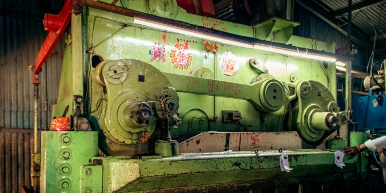 Large industrial shearing and pressing machine in a dimly lit workshop, similar to sheet metal punching equipment